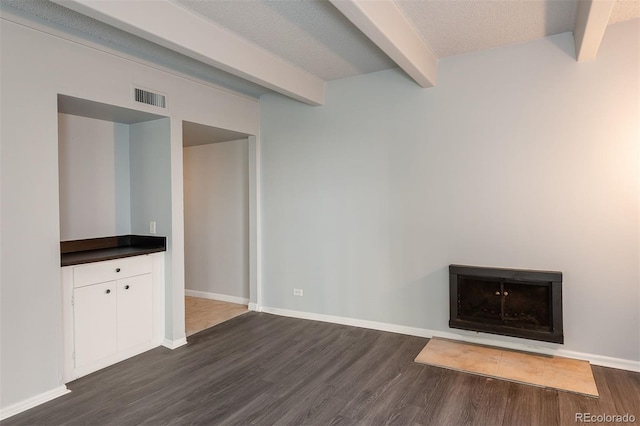 unfurnished living room featuring a textured ceiling, dark hardwood / wood-style floors, and beam ceiling