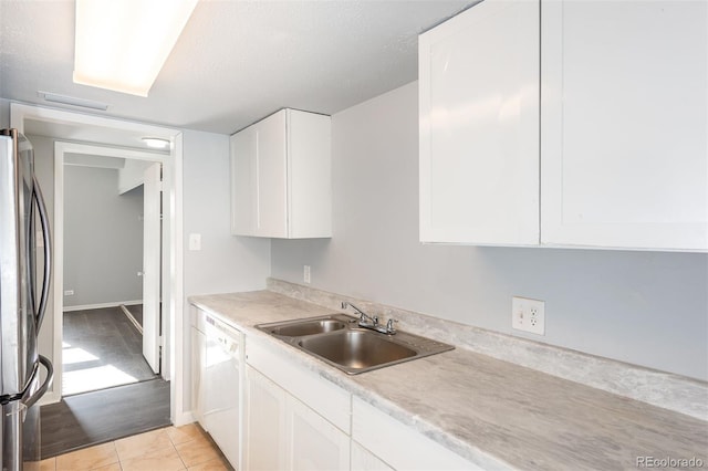 kitchen with light hardwood / wood-style floors, stainless steel refrigerator, sink, white dishwasher, and white cabinets