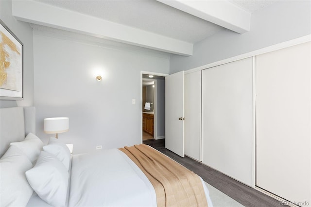 bedroom with a textured ceiling, a closet, beam ceiling, and dark hardwood / wood-style flooring