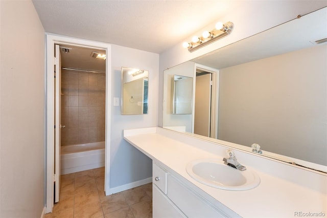 bathroom featuring tile patterned flooring, tiled shower / bath combo, vanity, and a textured ceiling