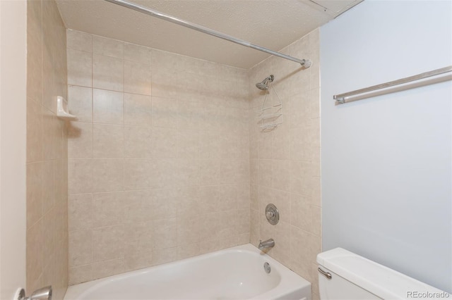 bathroom with tiled shower / bath, a textured ceiling, and toilet