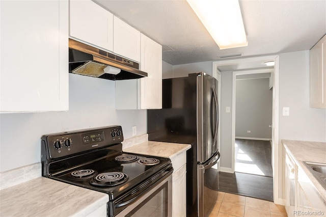 kitchen featuring electric range, white cabinets, light wood-type flooring, and a textured ceiling