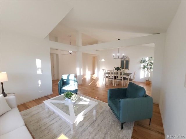 living area featuring light wood finished floors, a chandelier, and high vaulted ceiling