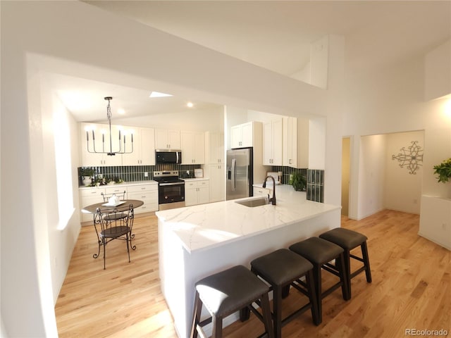 kitchen featuring a sink, light stone counters, stainless steel appliances, a peninsula, and a breakfast bar area