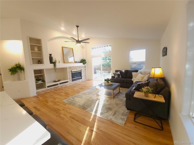 living area featuring light wood-style flooring, built in shelves, a ceiling fan, and vaulted ceiling