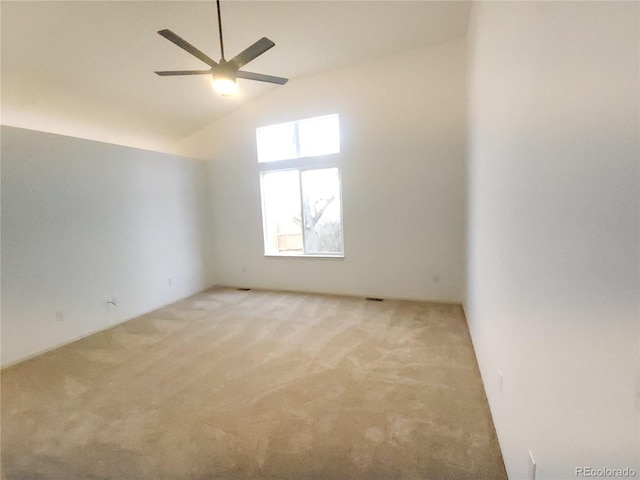 spare room featuring vaulted ceiling, a ceiling fan, and light colored carpet