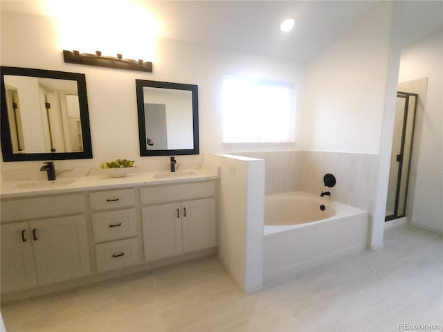 bathroom with a sink, a garden tub, a shower stall, and double vanity