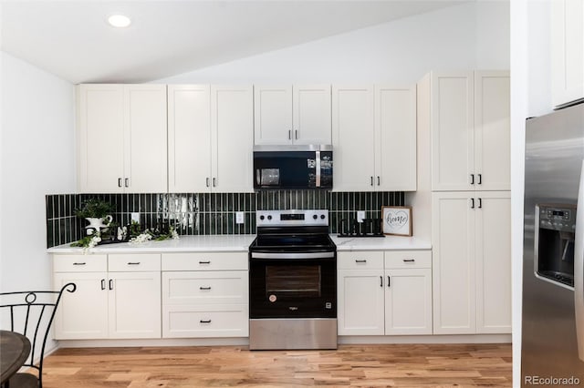 kitchen featuring vaulted ceiling, white cabinets, light countertops, and appliances with stainless steel finishes