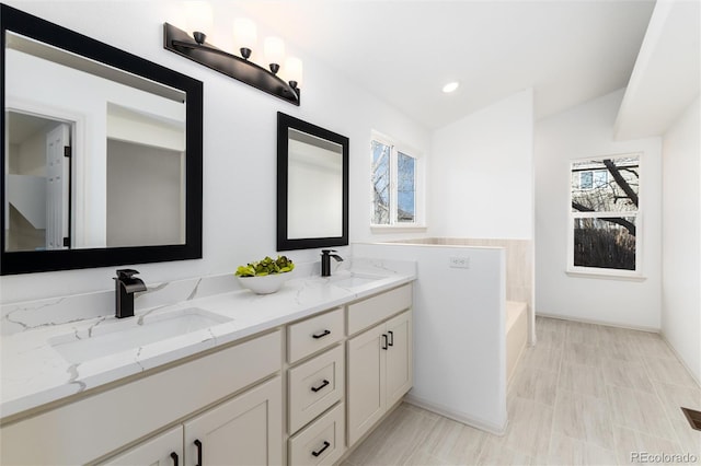 bathroom featuring double vanity, recessed lighting, a garden tub, and a sink