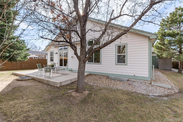 rear view of house featuring a patio area, a storage unit, an outbuilding, and fence