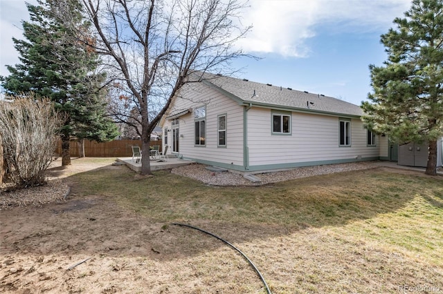 rear view of house with a patio, a lawn, and fence