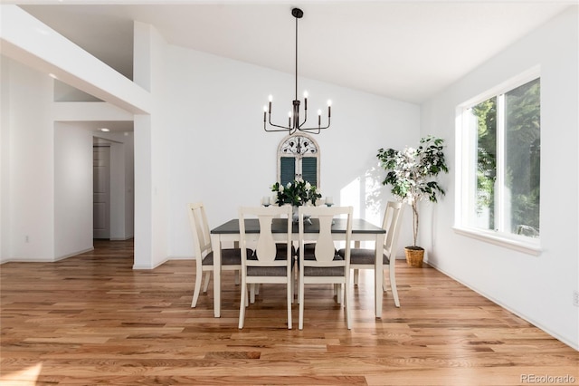 dining room with an inviting chandelier, light wood-style floors, and lofted ceiling