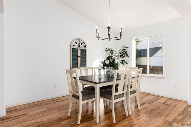 dining space featuring an inviting chandelier, light wood-style floors, and vaulted ceiling