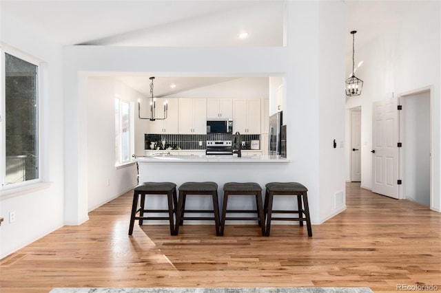 kitchen featuring white cabinetry, a kitchen breakfast bar, appliances with stainless steel finishes, and a chandelier