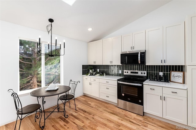 kitchen featuring appliances with stainless steel finishes, light wood finished floors, decorative backsplash, light countertops, and vaulted ceiling