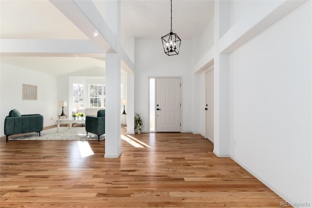 entrance foyer with light wood finished floors, a high ceiling, and an inviting chandelier