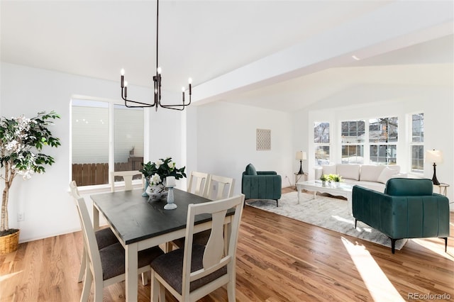 dining space featuring a notable chandelier, light wood-style flooring, and lofted ceiling