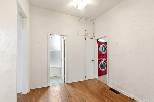 clothes washing area with ceiling fan, light hardwood / wood-style floors, and stacked washer and clothes dryer