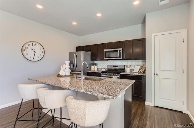 kitchen featuring sink, a center island with sink, a kitchen breakfast bar, stainless steel appliances, and backsplash