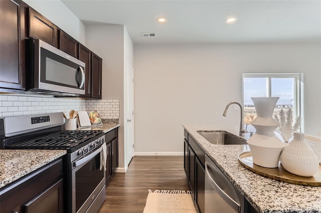 kitchen with dark hardwood / wood-style floors, sink, decorative backsplash, stainless steel appliances, and light stone countertops