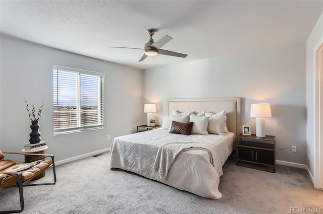 bedroom with a textured ceiling, light colored carpet, and ceiling fan