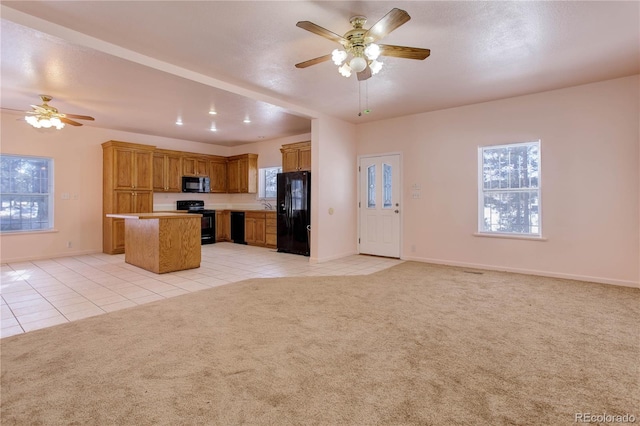 kitchen with ceiling fan, a center island, light carpet, and black appliances