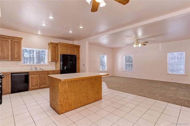 kitchen with black appliances, a kitchen island, light colored carpet, ceiling fan, and sink