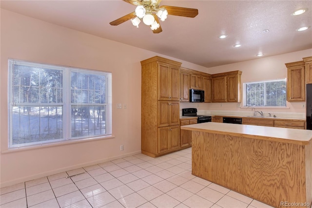 kitchen featuring sink, ceiling fan, light tile patterned floors, a kitchen island, and black appliances