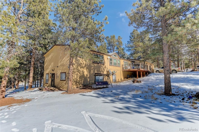 snow covered back of property with a wooden deck