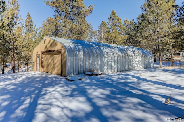 snow covered structure featuring a garage