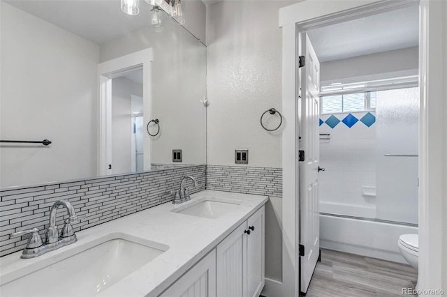 10609 Abilene St, Commerce City, CO 80022 - full bath featuring double vanity, tasteful backsplash, bath / shower combo with glass door, and wood finished floors
