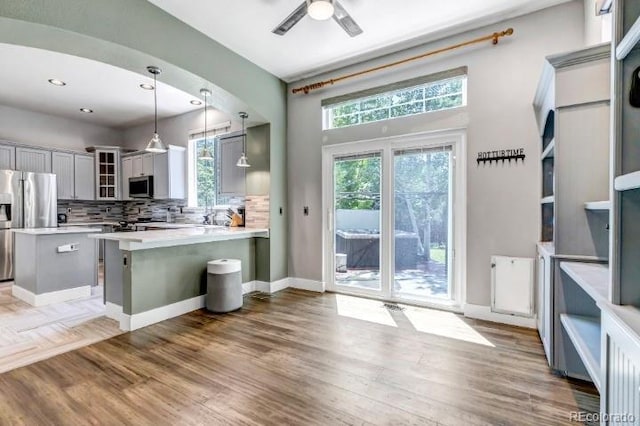 10609 Abilene St, Commerce City, CO 80022 - kitchen featuring appliances with stainless steel finishes, gray cabinets, glass insert cabinets, light countertops, and a peninsula