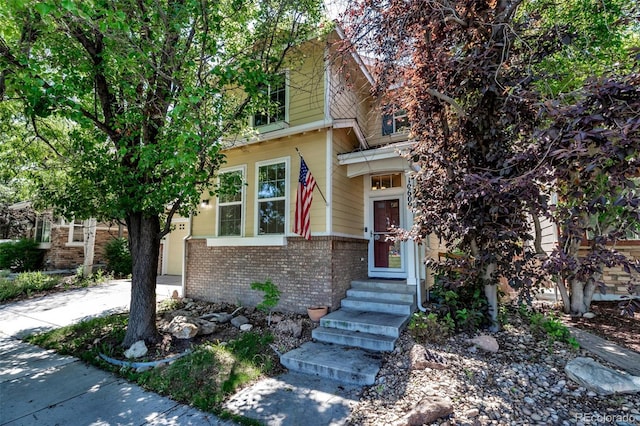 10609 Abilene St, Commerce City, CO 80022 - view of property hidden behind natural elements with brick siding, entry steps, and driveway
