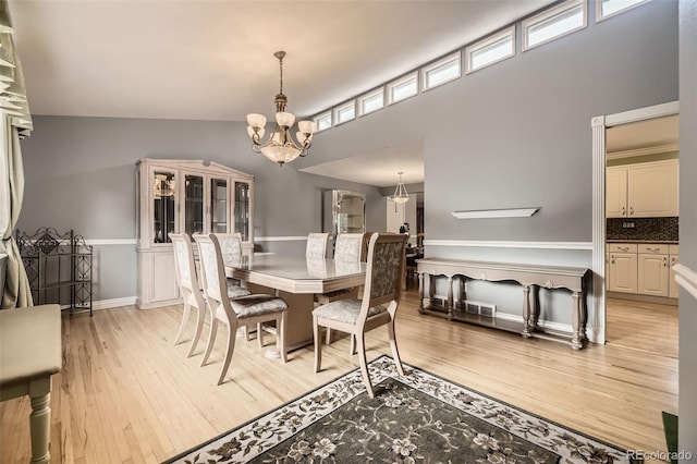 6072 Pierson Ct, Arvada, CO 80004 - dining space featuring light wood-style flooring, a chandelier, and a towering ceiling