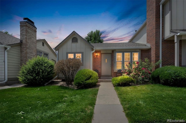 9642 W Chatfield Ave Unit A, Littleton, CO 80128 - view of front of property featuring board and batten siding, a yard, brick siding, and a chimney