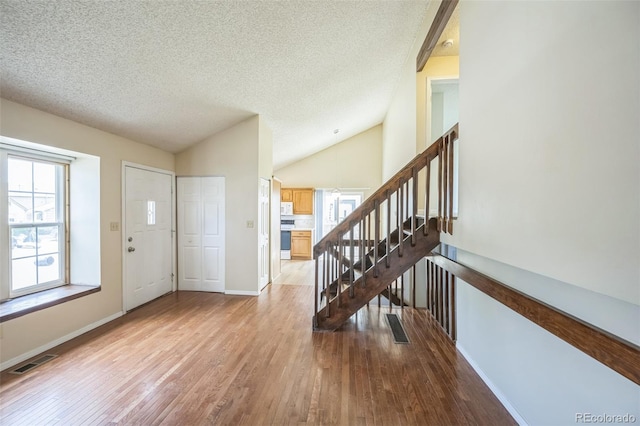 9642 W Chatfield Ave Unit A, Littleton, CO 80128 - foyer with a textured ceiling, wood finished floors, lofted ceiling, and stairway