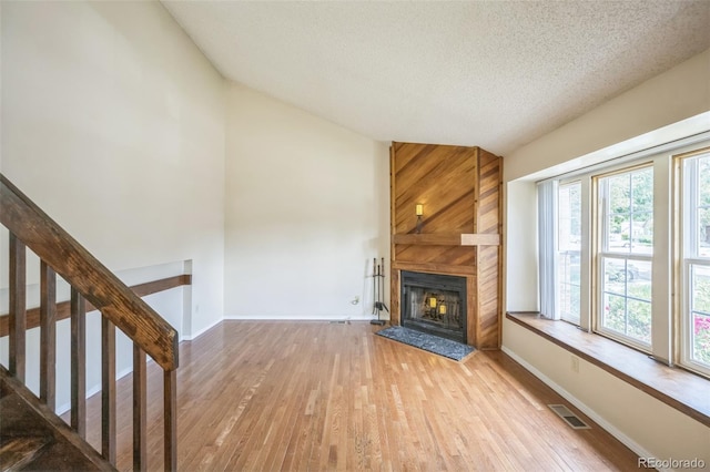 9642 W Chatfield Ave Unit A, Littleton, CO 80128 - unfurnished living room featuring lofted ceiling, wood finished floors, a large fireplace, a textured ceiling, and stairway