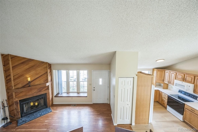 9642 W Chatfield Ave Unit A, Littleton, CO 80128 - kitchen featuring white appliances, a textured ceiling, a fireplace, light countertops, and light wood finished floors