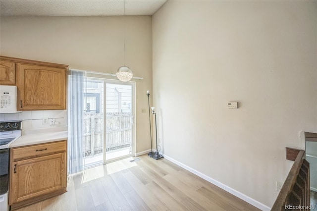 9642 W Chatfield Ave Unit A, Littleton, CO 80128 - kitchen featuring white appliances, light wood-style floors, high vaulted ceiling, light countertops, and pendant lighting