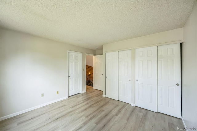 9642 W Chatfield Ave Unit A, Littleton, CO 80128 - unfurnished bedroom with two closets, light wood-type flooring, and a textured ceiling
