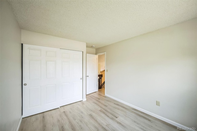 9642 W Chatfield Ave Unit A, Littleton, CO 80128 - unfurnished bedroom featuring light wood-style floors, a closet, and a textured ceiling