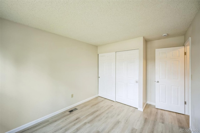 9642 W Chatfield Ave Unit A, Littleton, CO 80128 - unfurnished bedroom with light wood-type flooring, a closet, and a textured ceiling