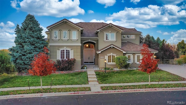 traditional home with stucco siding and a front lawn