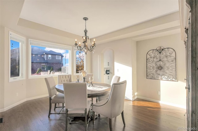 dining space with baseboards, a notable chandelier, arched walkways, and dark wood-type flooring