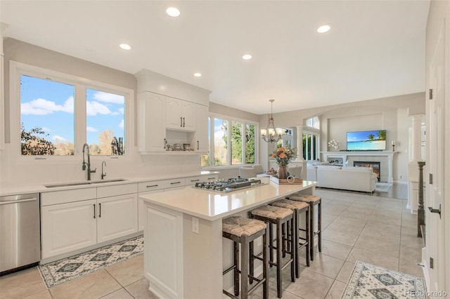 kitchen with a sink, a breakfast bar, white cabinetry, a center island, and appliances with stainless steel finishes