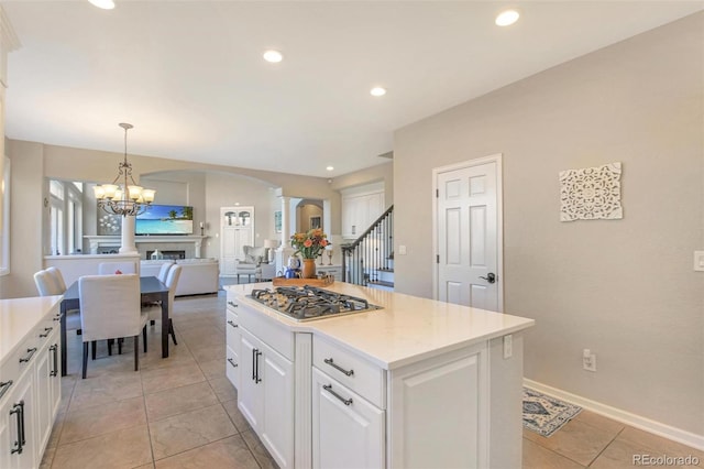 kitchen featuring light countertops, white cabinetry, arched walkways, and stainless steel gas cooktop