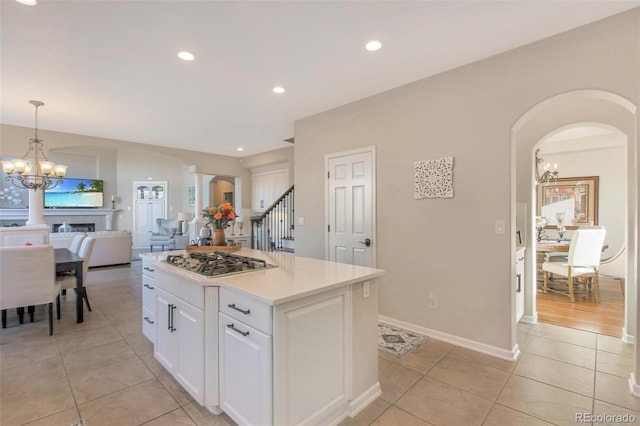 kitchen featuring stainless steel gas stovetop, white cabinetry, a notable chandelier, and light tile patterned floors