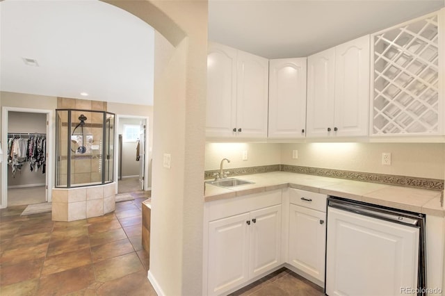 kitchen with dishwasher, light countertops, white cabinetry, and a sink