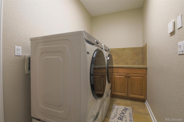 laundry area with washer and clothes dryer, light tile patterned flooring, and cabinet space