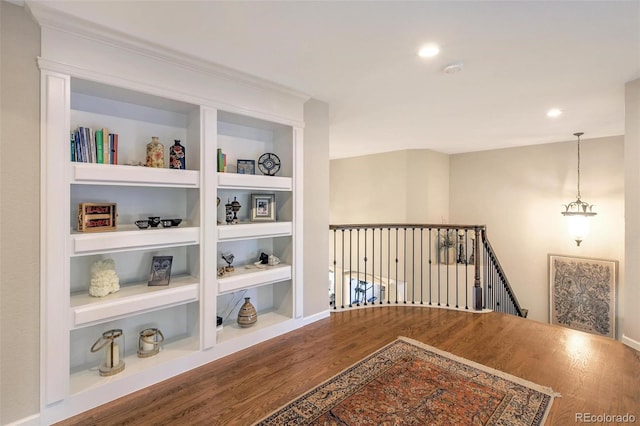hall featuring wood finished floors, an upstairs landing, built in features, recessed lighting, and baseboards